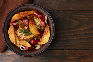 Delicious baked potato with thin dry smoked sausages, onion and dill in bowl on wooden table, top view. Space for text