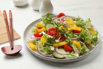 Tasty fresh vegetarian salad and chopsticks on white marble table, closeup