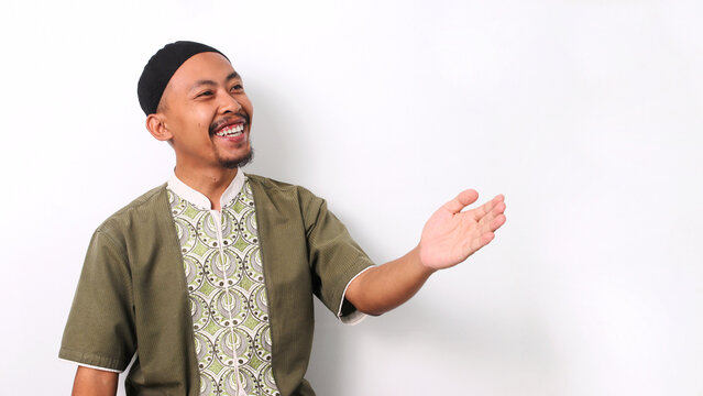 Indonesian Muslim man in koko shirt and peci extends his arms wide in a welcoming gesture, leaving space for text or advertisement. Isolated on a white background