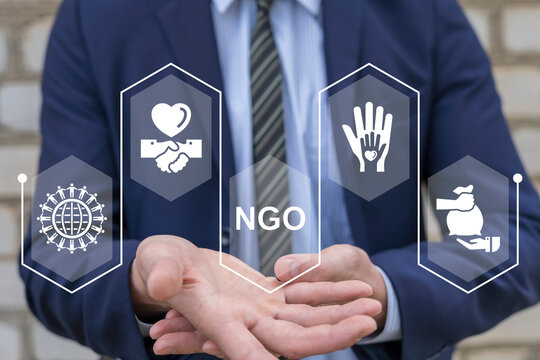 Businessman using virtual interface sees text: NGO. Non-governmental, nonprofit organizations work concept. NGO and volunteers. Humanitarian aid, donation, international support and solidarity.