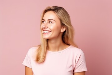 Portrait of a happy young woman looking up over pink background.