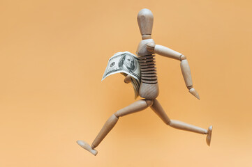 A wooden man runs away with money from someone. Concept of theft, financial pyramid, winning the lottery, cashback, value added tax refund.