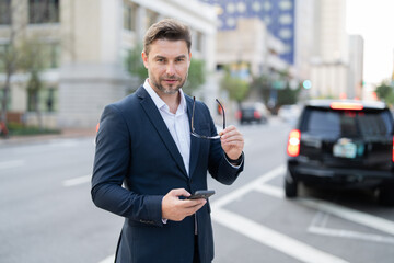 Businessman with backpack walking in city. Side view of male entrepreneur in classy suit and with takeaway drink walking along crosswalk while commuting to work in morning. businessman in the street