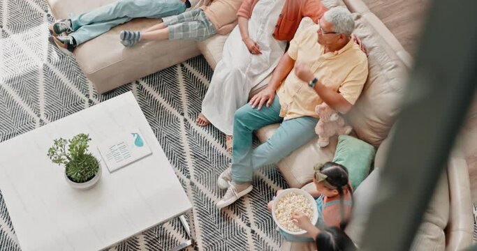 Family, popcorn and watching tv on sofa in living room of home from above for bonding or visit. Grandparents, parents and children talking in apartment together for subscription television streaming