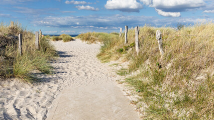 Weg mit Zäunen durch Dünen mit Strandhafer zum Strand an der Ostsee mit blauem Himmel mit Wolken bei Heiligenhafen, Schleswig-Holstein