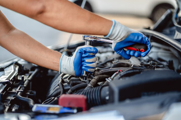 Obraz premium Close up of view Auto mechanic repairman using a socket wrench working engine repair in the garage, changing spare parts, checking the mileage of the car, checking and maintenance service concept.