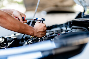Close up of view Auto mechanic repairman using a socket wrench working engine repair in the garage,...
