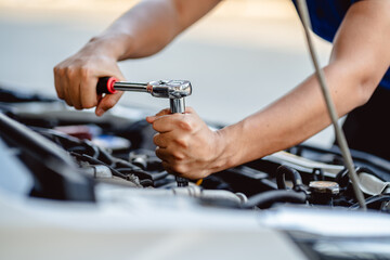 Close up of view Auto mechanic repairman using a socket wrench working engine repair in the garage,...