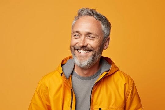 smiling middle aged man in yellow jacket over yellow background, portrait