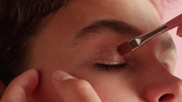Eye shadow makeup to the upper eyelid, close-up. Makeup artist applies a bright eye shadow with a makeup brush.Tutorial master class of professional makeup. 