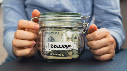 Unrecognizable woman holding Saving Money In Glass Jar filled with Dollars banknotes. COLLEGE...