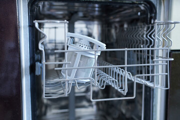Empty dishwasher in the kitchen. Dishwasher filter. Selective focus. Shallow depth of field