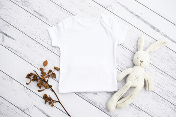 Blank baby bodysuit half mock up on wood background with dried flowers and toy