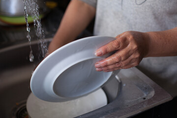 Incognita photograph of hands washing a dish in South America.