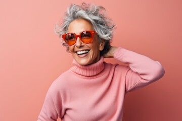 Cheerful senior woman with grey hair wearing pink sweater and sunglasses