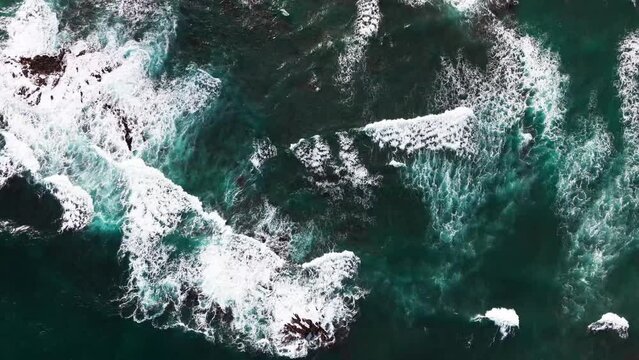 drone parallax shot of violent and powerful waves crashing onto the rocks on a windy and overcast day on the coastline of hawaii.