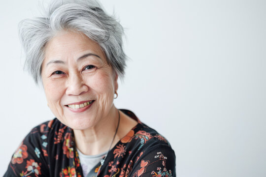 Portrait of old healthy, cheerful beautiful Asian woman smiling and looking at camera with white background. Happy aging society, retirement and senior healthcare concept