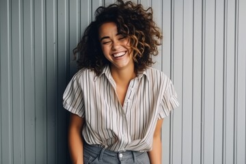 Portrait of a beautiful young woman laughing against a metal wall.