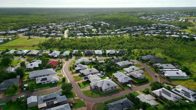 Aerial drone of tropical suburb neighborhood surrounded by lush forest on sunny day
