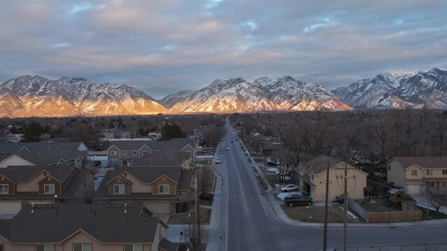 Flying over streets facing towards mountains at sunset in Midvale Utah neighborhood