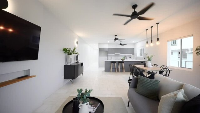 Sleek Elegant Modern Luxurious Grey Apartment Interior Loungeroom Living Room and Kitchen With Ceiling Fan and Over Table Lighting. Interior of house home for real estate property.