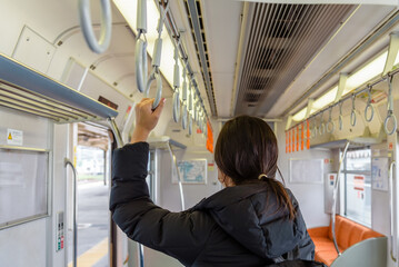 Asian woman passenger holding the handle in tram, train, bus or subway.