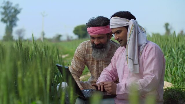 Modern villagers discussing cultivation plans in a wheat field - agriculture  farming  farmers  checking farm subsidy . A young Indian farmer checking farming techniques online - use of technology ...