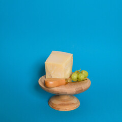 parmigiano käse, Käsemesser und trauben auf dem holztablett und buntem hintergrund