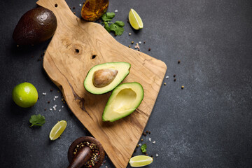 Halved green avocado fruit on wooden cutting board at domestic kitchen
