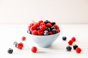 Ripe sweet blueberries and raspberries in a bowl. Closeup.