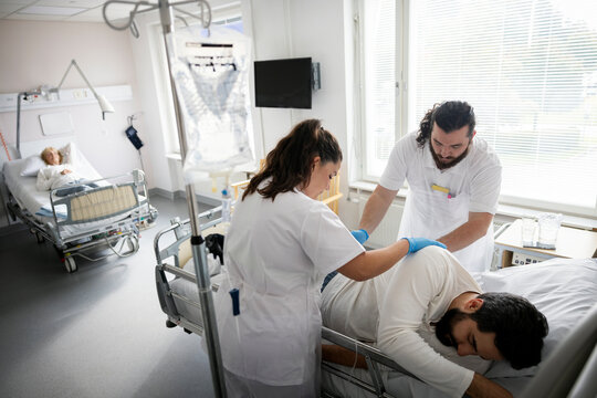 Male and female doctors examining patient lying on bed in hospital