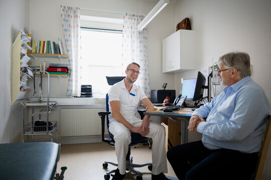Smiling male doctor discussing with senior patient in clinic