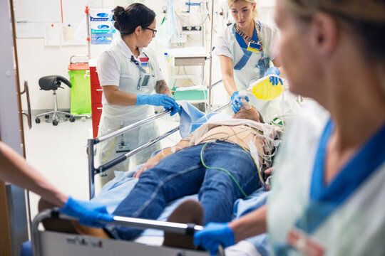 Female doctor putting oxygen mask on male patient by nurses for emergency treatment in hospital
