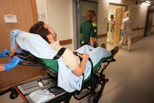 Female paramedics pushing male patient on gurney for emergency treatment in hospital