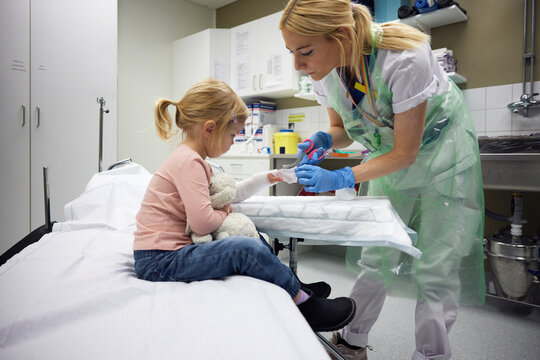 Female orthopedic tying bandage on girl's hand in hospital