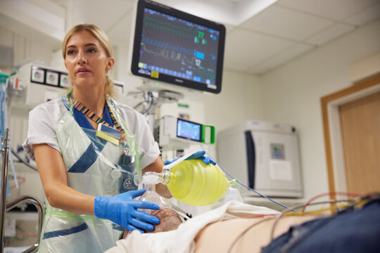 Female cardiologists putting oxygen mask on male patient for electrocardiography in hospital