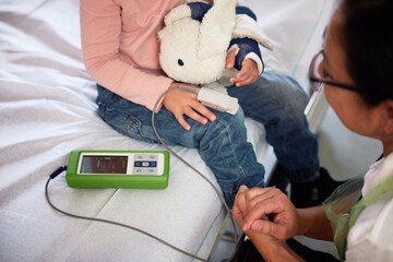 Female pediatrician checking oxygen saturation level of girl in hospital