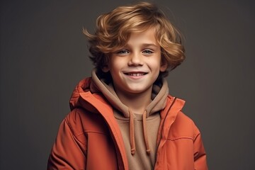 Portrait of a cute little boy with blond curly hair in a red jacket.