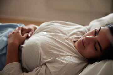 Young female patient lying on bed in ward at hospital