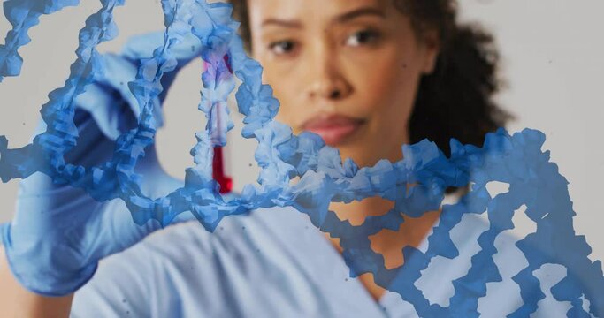 Animation of blue dna strand over biracial female doctor holding blood sample