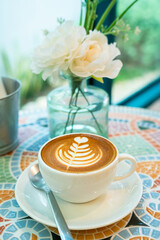 Hot coffee latte with latte art milk foam in cup mug on marble floor desk As breakfast In a coffee shop at the cafe, during business work concept