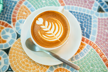 Hot coffee latte with latte art milk foam in cup mug on marble floor desk As breakfast In a coffee shop at the cafe, during business work concept