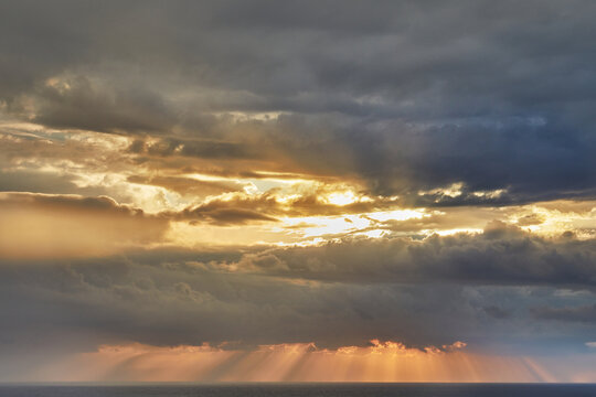 Dramatic thunderclouds over mediterranean sea with sun rays breaking through