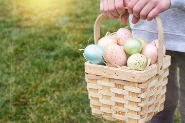 Easter basket with eggs in a child's hands. Sun rays