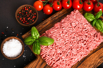 Minced pork and beef on a wooden board. Minced meat with spices on a dark background
