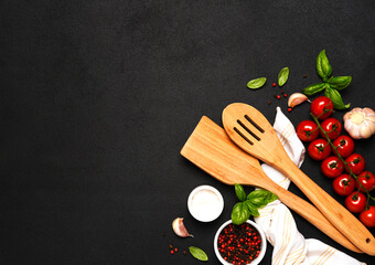 Spatula and kitchen towel and tomatoes on a black background. Food background - 752041602