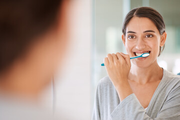 Woman, brushing teeth and smile in morning by mirror for health, wellness or self care for breath...