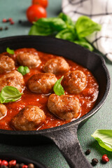 .Meatballs with tomato sauce and basil in a frying pan