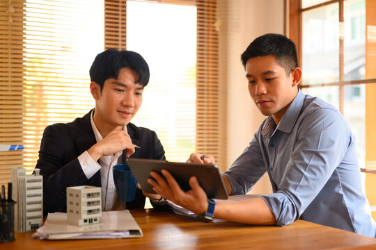 Architects men looking at digital tablet while working with architectural model model at office