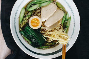 A bowl of ramen with chicken and asparagus